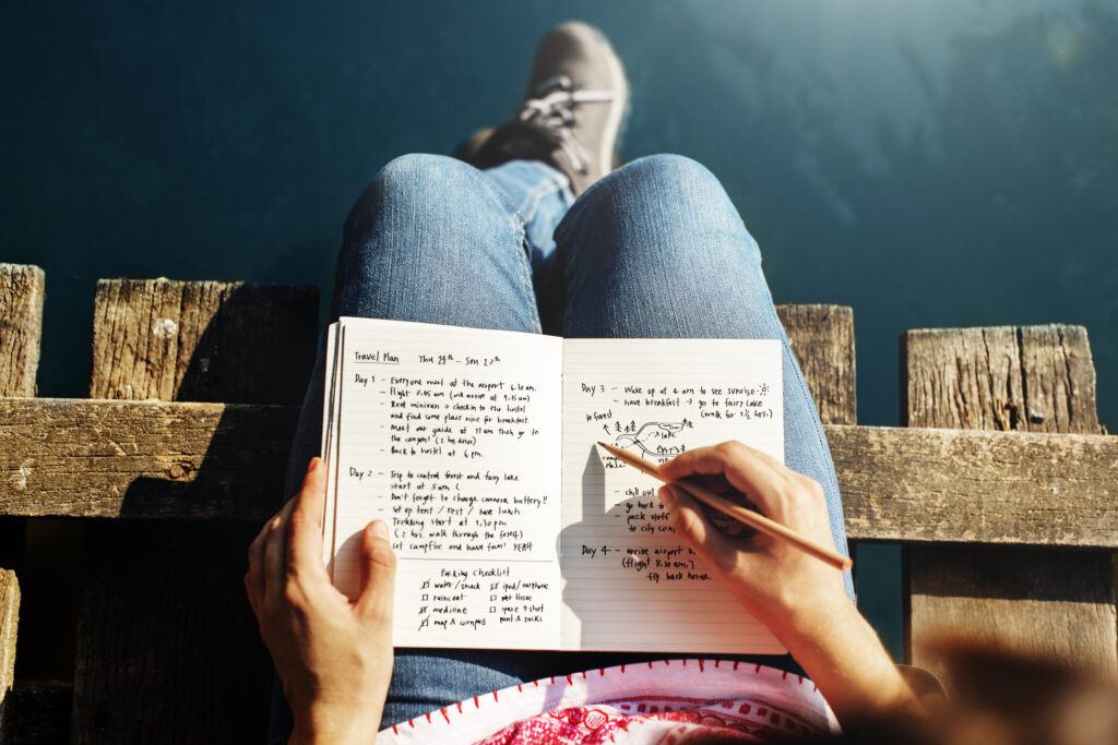 a women sitting writing a short story on a notebook